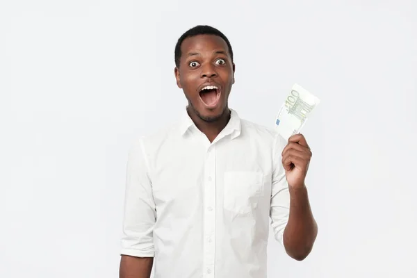 Young rich african american man in shirt holding one hundred euro with surprise — Stock Photo, Image