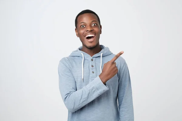 Молодой африканский парень улыбается и указывает пальцем в сторону — стоковое фото