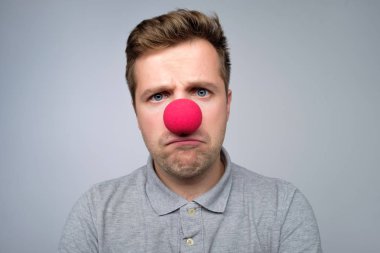 Mature caucasian man wearing clown red nose isolated on gray background clipart