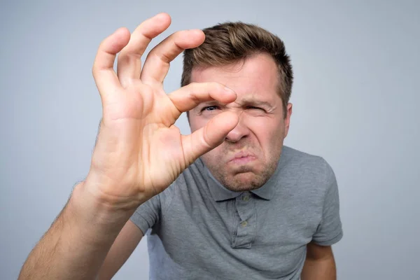 Молодий білий чоловік жестикулює рукою, показуючи знак малого розміру пальцями . — стокове фото
