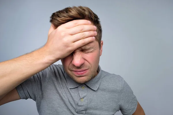 man showing how much his head hurts, suffering from pain