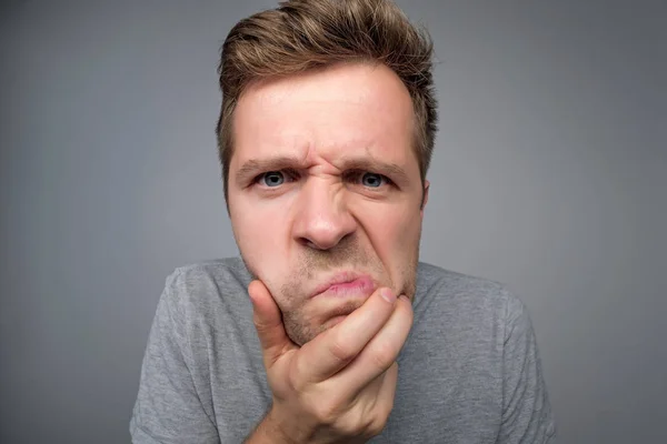 man keeps lips pressed has frustrated frowned face