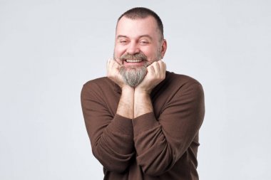 Çene yakın kollarını tutan sakallı mutlu olgun adam.