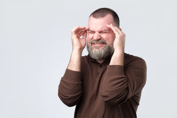 Hombre maduro que sufre de dolor de cabeza severo, presionando los dedos a las sienes , —  Fotos de Stock