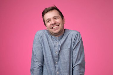 Yakışıklı genç adam pembe arka plan üzerinde gülüyor