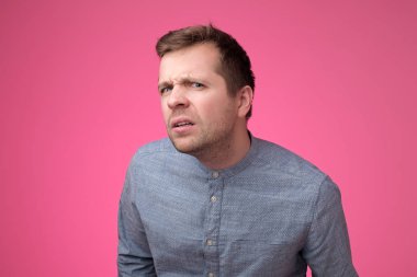 Şaşırmış ve şok genç adam kötü haber işitme, pembe duvar üzerinde şüpheli olmak