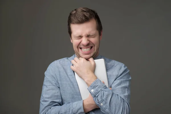 shocked man hugs a tablet on a gray background