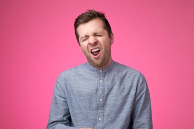 Yorgun adam uykulu hissediyor, yorgun hissediyor gibi esneme, yaygın ağız açılır, pembe arka plan üzerinde pozlar.