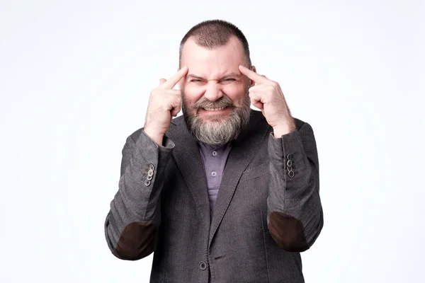 Hombre con un dedo en la sien, difícil de pensar y tratar de resolver un problema grave, retorciéndose de dolor — Foto de Stock