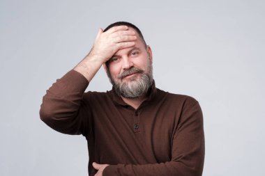 Elini yoran alnını silen adam.