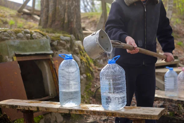 Blanke man met behulp van Scoop tekening water uit oude put — Stockfoto