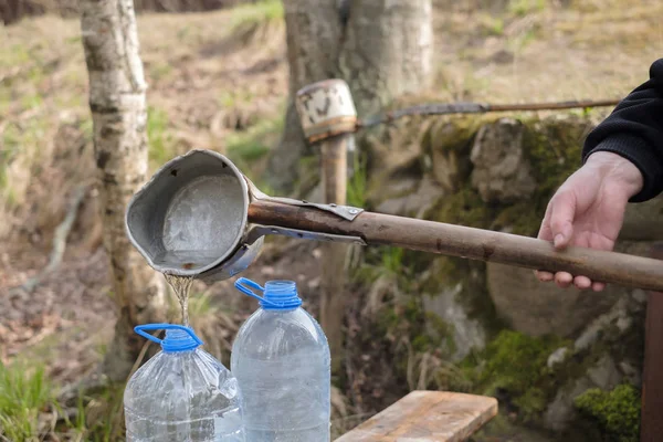 Kaukaski mężczyzna za pomocą czerpak rysunek wody ze starych studni — Zdjęcie stockowe