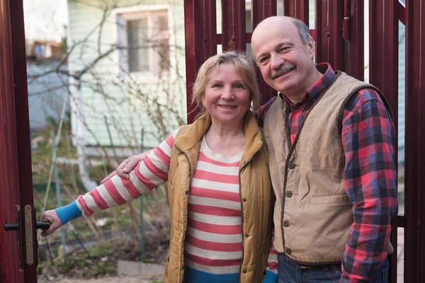 Seniorenpaar steht lächelnd am Zaun im Hof. — Stockfoto