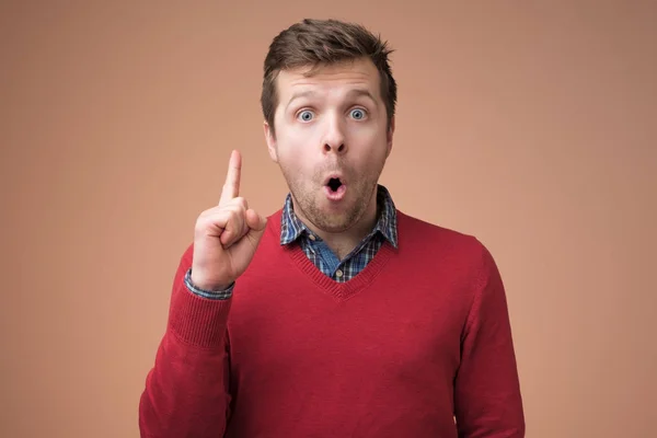 Attractive young man in red sweater pointing up with his finger — Stock Photo, Image