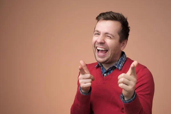 Europejski młody człowiek w czerwonym swetrze śmieje się na zabawny żart — Zdjęcie stockowe
