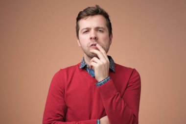 Kırmızı kazaklı genç bir adam seçim yapmaya çalışıyor..