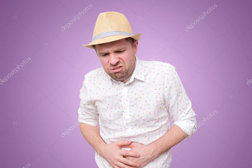 Young man in summer hat with stomach pain indigestion