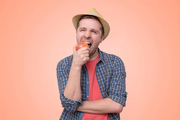 Muž v letním klobouku a namazat červený jablko. — Stock fotografie