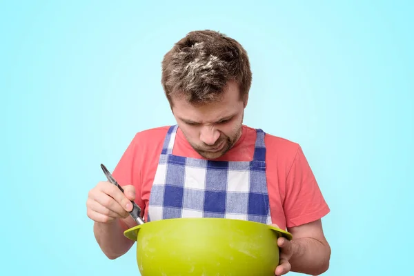 Hombre sostiene utensilios de cocina de cocina con cara curiosa —  Fotos de Stock