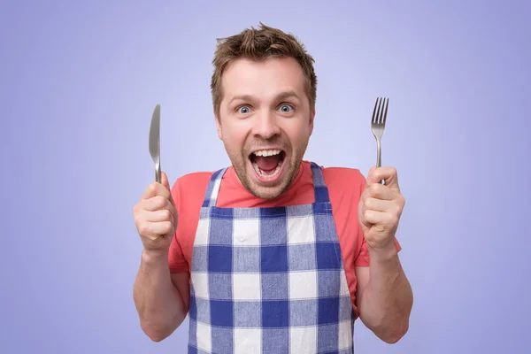 Man in apron holding cutlery fork and knife — Stock Photo, Image