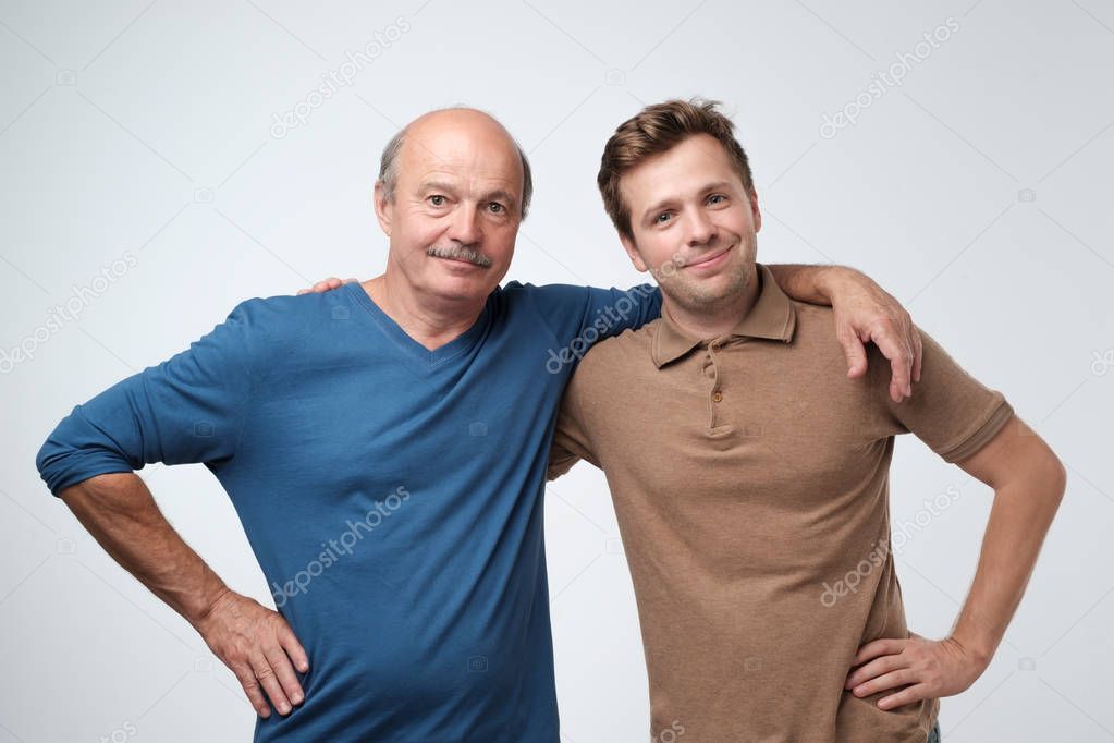 Cheerful father and son hugging and posing together