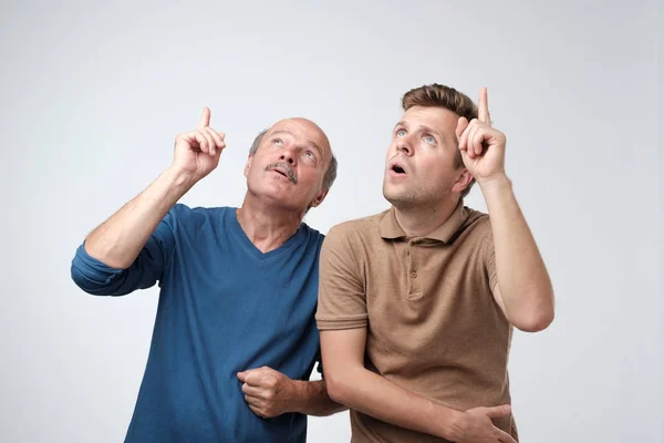 Vater und Sohn blicken mit erhobenem Zeigefinger erschrocken und verängstigt nach oben . — Stockfoto