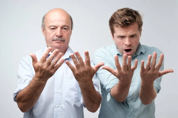 Pai e filho olham para as palmas das mãos com choque — Fotografia de Stock