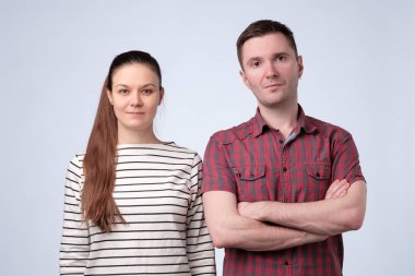 Gri stüdyo duvarında ciddi Avrupalı çift birlikte ayakta.
