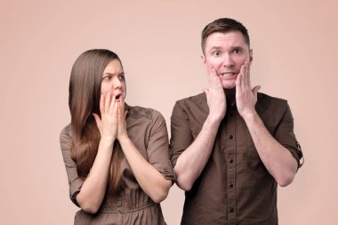 Woman and man in brown clothes are shocked, amazed, surprised