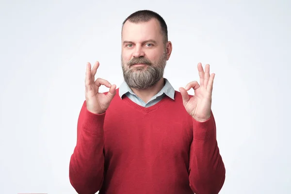 Dospělý muž v červeném svetru se znakem OK — Stock fotografie