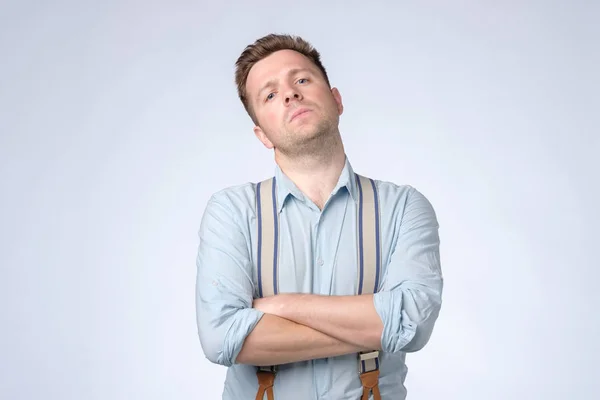 Homme égoïste sérieux avec les bras croisés et les bretelles posant au studio . — Photo