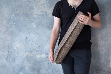 Closeup erkek el parlak gri arka plan üzerinde yoga mat tutan, kopya alanı.