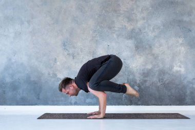 Sportif genç adam çalışma, handstand yoga asana, Crow Pose veya Bakasana yapıyor