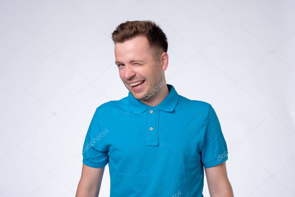 Happy sly man in blue t-shirt winking an eye