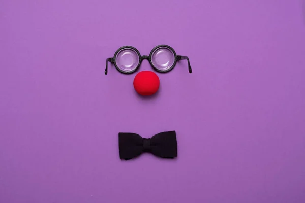 Occhiali divertenti, naso da clown rosso e cravatta sdraiati su uno sfondo colorato, come un viso . — Foto Stock