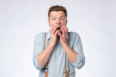 Young man covering mouth with hands and round eyes experiencing deep astonishment clipart
