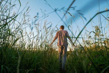 Genç adam tarlada tek başına yürüyor.