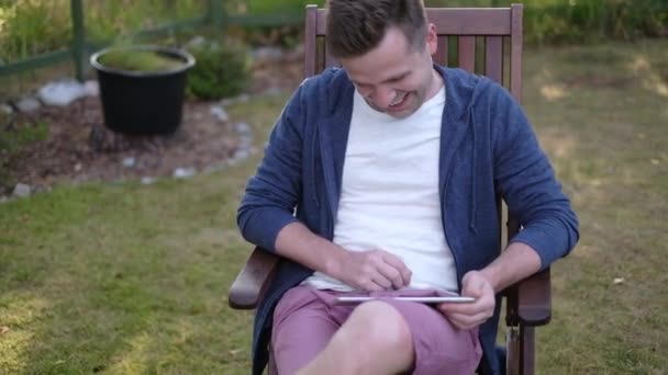 Jovem caucasiano lendo ao ar livre, rindo, conversando — Vídeo de Stock