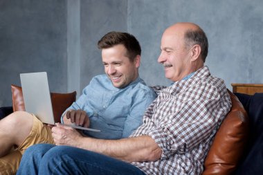 ather ve olgun oğlu birlikte koç otururken dizüstü ekran bakarak.