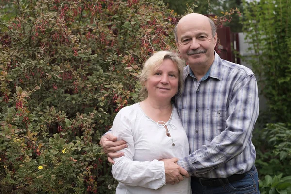 Glad äldre par vilar i grön sommarträdgård — Stockfoto