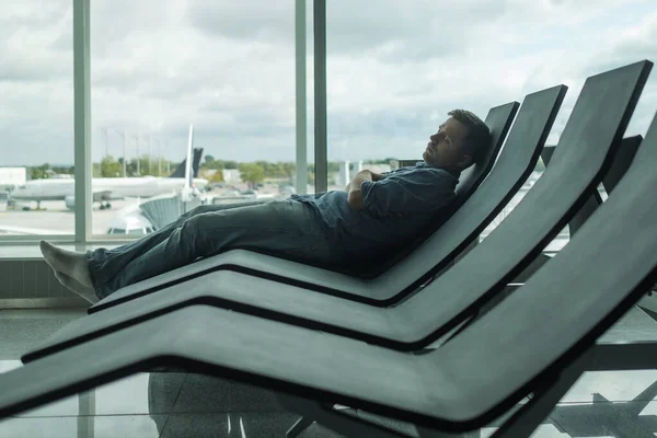 Mature man in airport sleeping on a bench