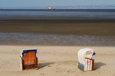 Cuxhaven, Almanya - 06 Ekim 2019: Sahilde çatıya vurulan hasır plaj sandalyesi