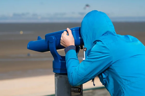 Hombre de abrigo azul mirando el mar usando moneda operado viewe binocular — Foto de Stock
