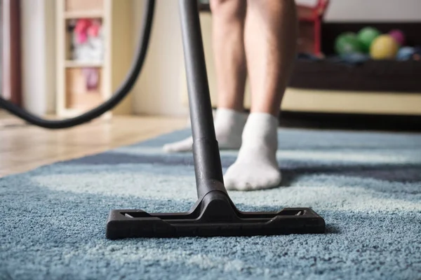 Man cleaning from dust a carpet. No face