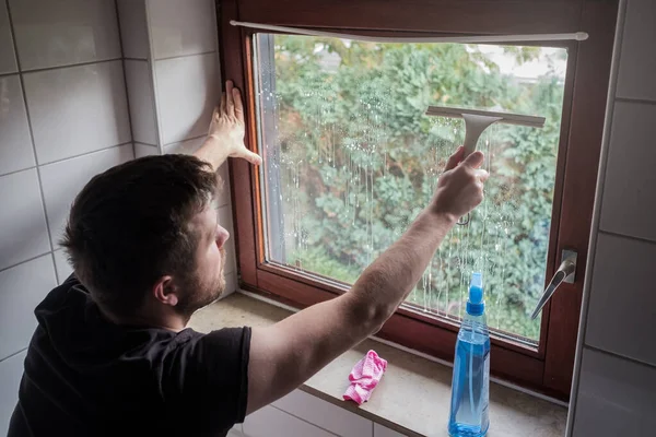 Mann wäscht Fenster eines Hauses mit Schaber — Stockfoto