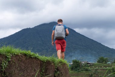 Beyaz adam çayırda tek başına yürüyor. Arka görünüm.