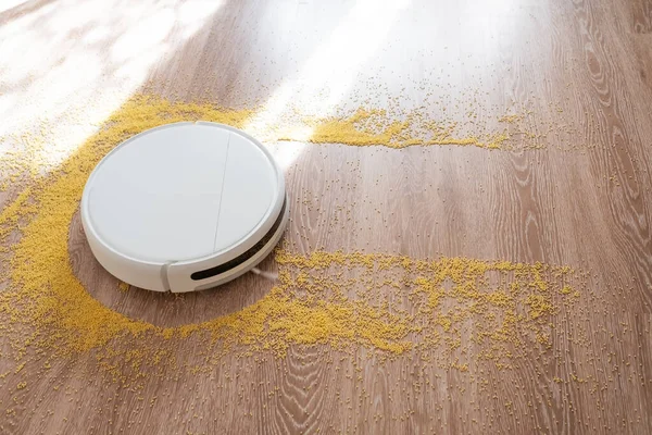 Aspirador de pó robô branco em um piso de madeira grãos de limpeza . — Fotografia de Stock