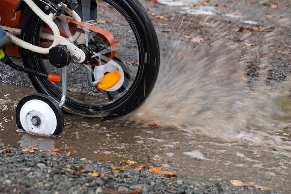 Bisiklet sürmeyi öğrenmek için su birikintisinde bisiklet sürmek.. — Stok fotoğraf
