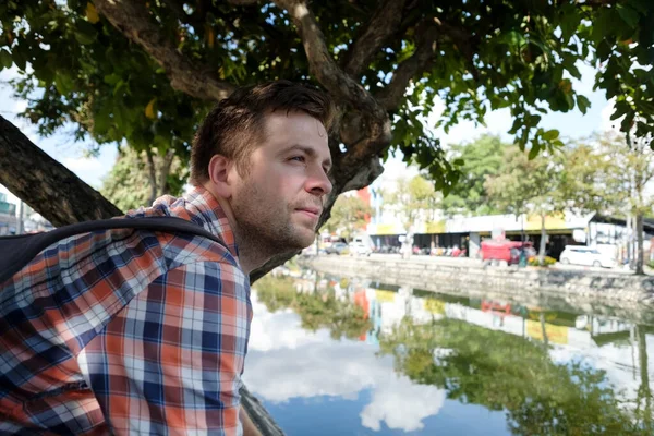 Человек, сидящий на набережной реки в городе — стоковое фото