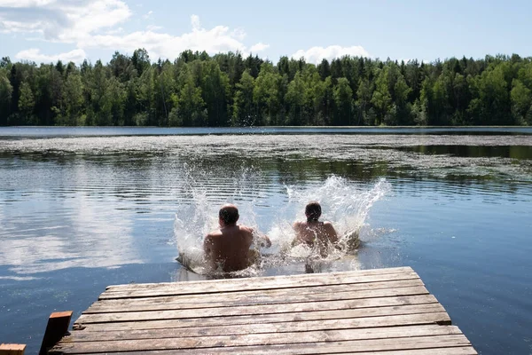 Mężczyzna i kobieta skaczą do jeziora podczas wakacji — Zdjęcie stockowe
